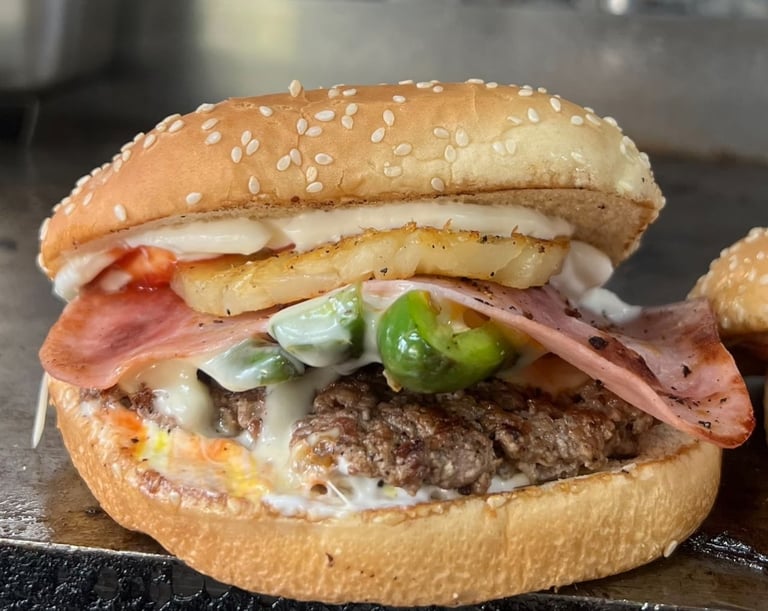 Gourmet burger with sesame seed bun, beef patty, bacon, fried egg, cheese, and jalapeño slices on dark surface
