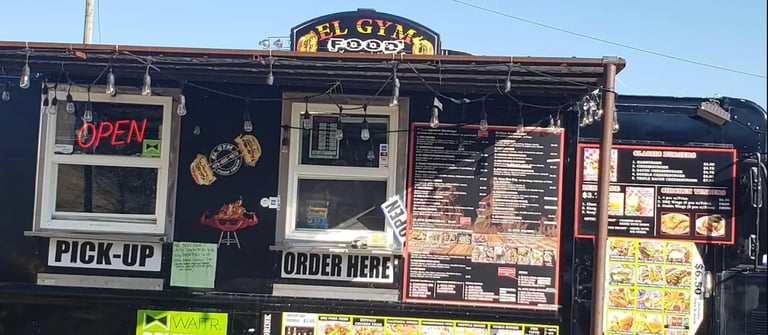 El Gyro food truck with open sign, pick-up window, and menu boards displaying food options and prices.